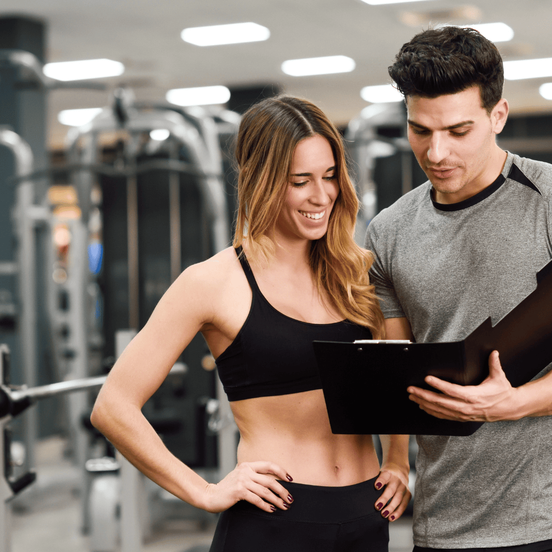 Chica feliz en gimnasio con un entrenador